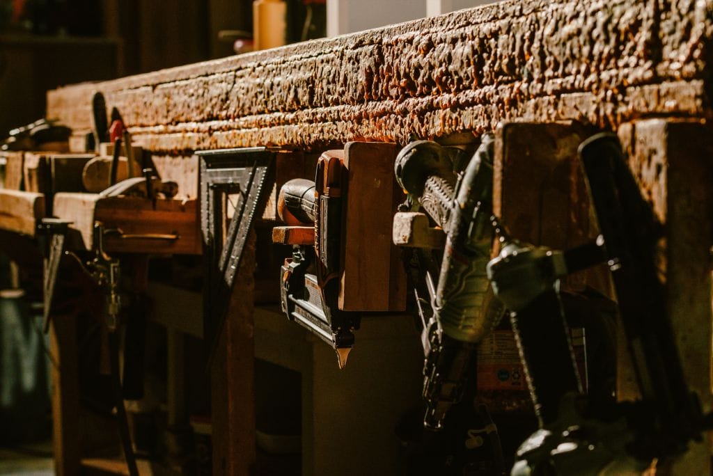 Carpenter’s workbench with a speed square, nail guns and hand tools hanging along its edge