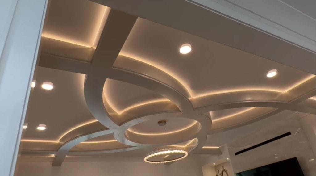 Custom ceiling with intersecting curved beams, glowing cove lighting and a ring chandelier