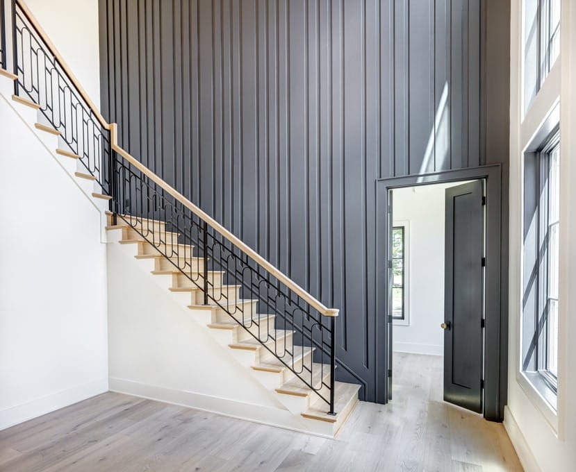 Vertical board-and-batten accent wall beside an open staircase with black metal balusters