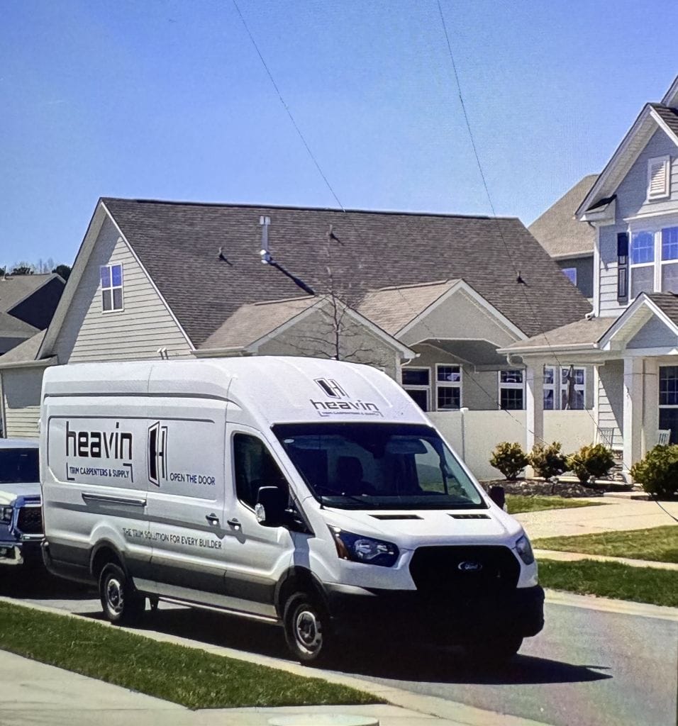 White Heavin Trim Carpenters & Supply work van parked outside new homes in a residential community